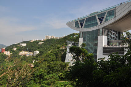 Modern Peak Tower on Victoria Peak, Hong Kong Island, with glass architecture overlooking forested hills and urban skyline